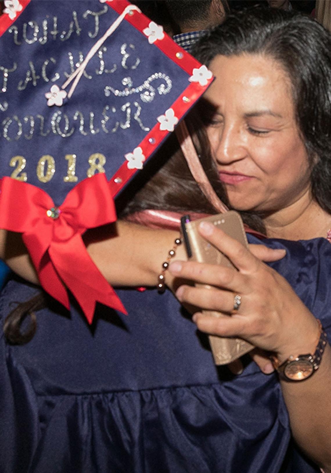 Photo of a student and their relative hugging each other following a graduation ceremony