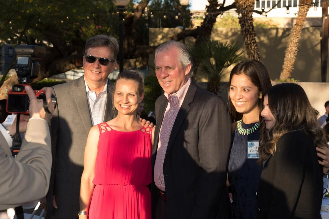 UA President Robert C. Robbins poses for a photo with guests and community leaders at the annual Portraits of Excellence event, all are facing away from the camera