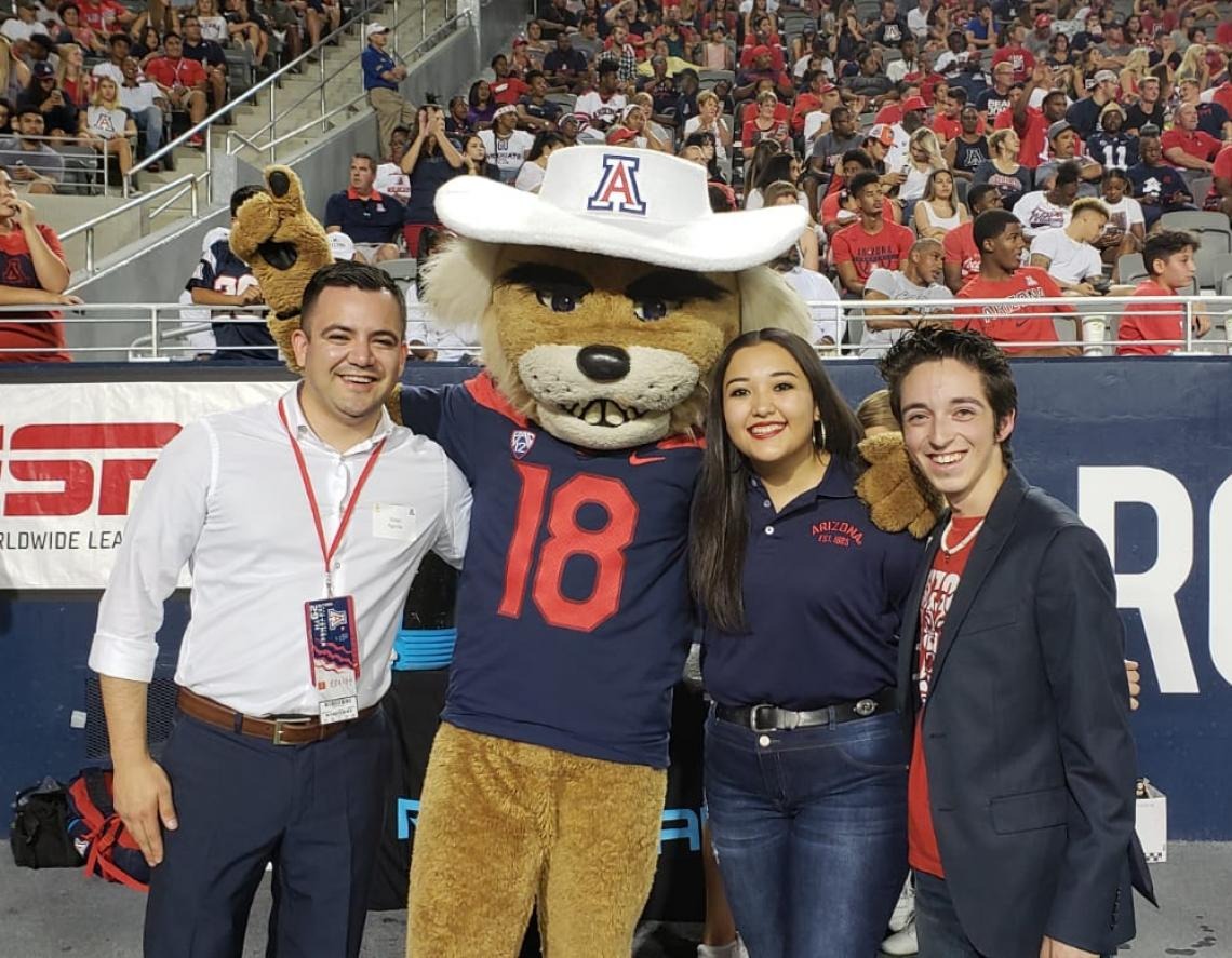 The President of the Hispanic Alumni Club takes a photo on the football field with Wilbur and two students recognized by UAHA for their academic achievements, Nathan is featured on the right
